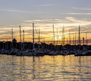 Skipperservice für Segelurlaub: Ansicht eines Hafens mit vielen Segelbooten in Abendstimmung